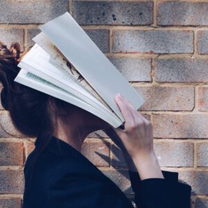 Person, die sich ein Buch vor den Kopf hält - Titelbild des Blogbeitrags "Betreuung in Selbstlern-Phasen: Praxis-Tipps für Lehrende"